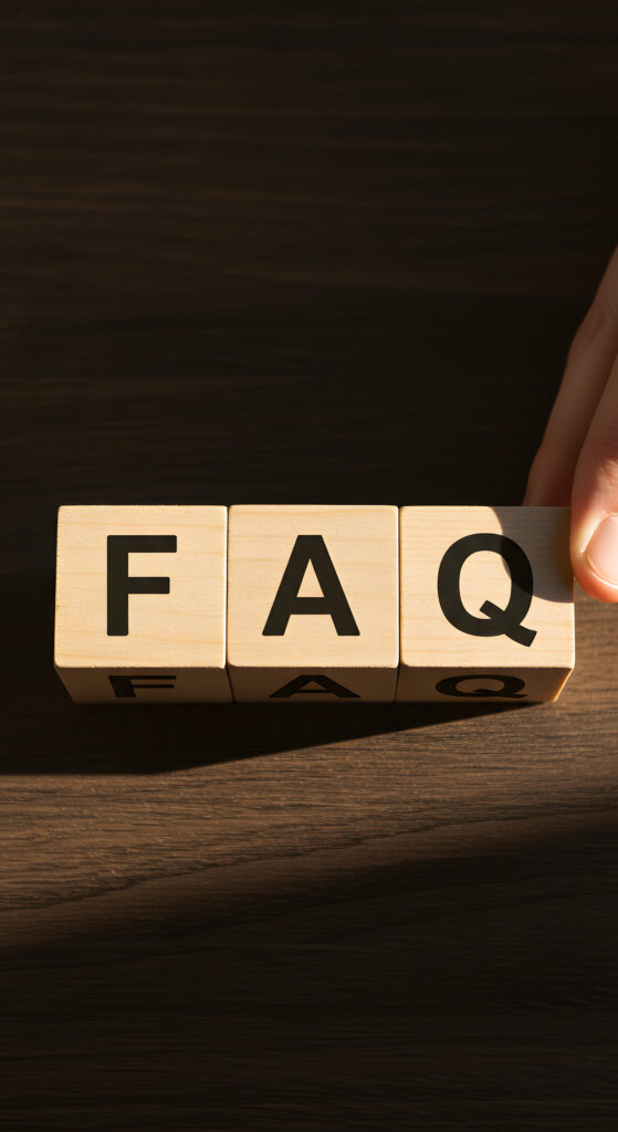 Three wooden blocks on a dark surface spell out "FAQ" in bold black letters. A hand is touching the rightmost block. The blocks cast shadows on the surface.